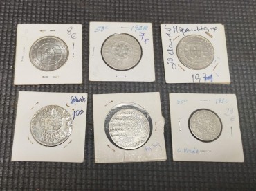 Seis moedas sendo 50 centavos de Cabo Verde, 20 escudos de Moçambique de 1955, 1960 e 1971, 50 centavos de 1928 de Angola e 20 escudos de 1971