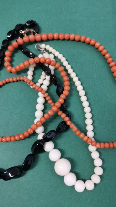 Três colares em tons de preto, branco e coral